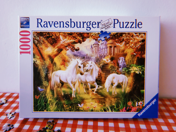 A photo of a Ravensburger puzzle which shows a soft, idyllic image of three unicorns in a woodland setting.
