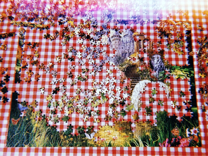 A photo of a half-finished unicorn puzzle on a red and white checkered tablecloth.